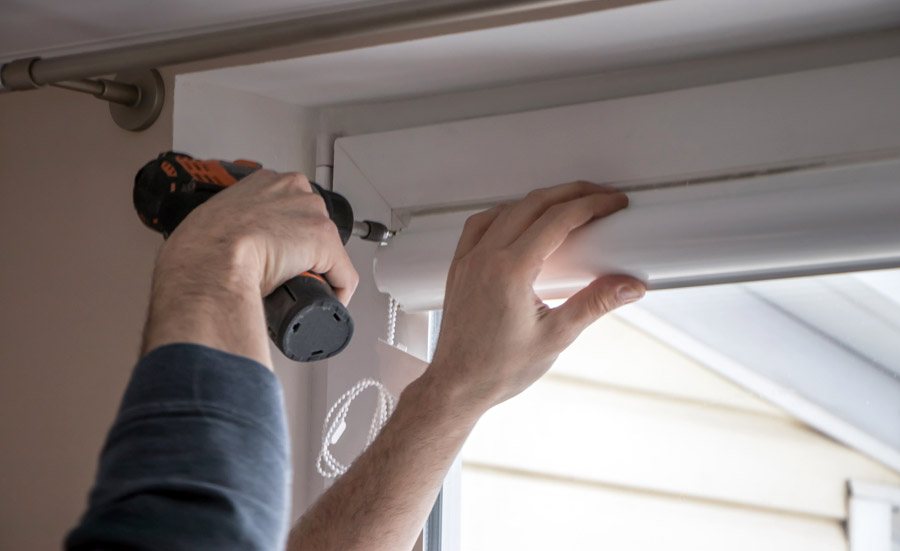 Zwei Monteure setzen einen Rollladenkasten am Fenster ein